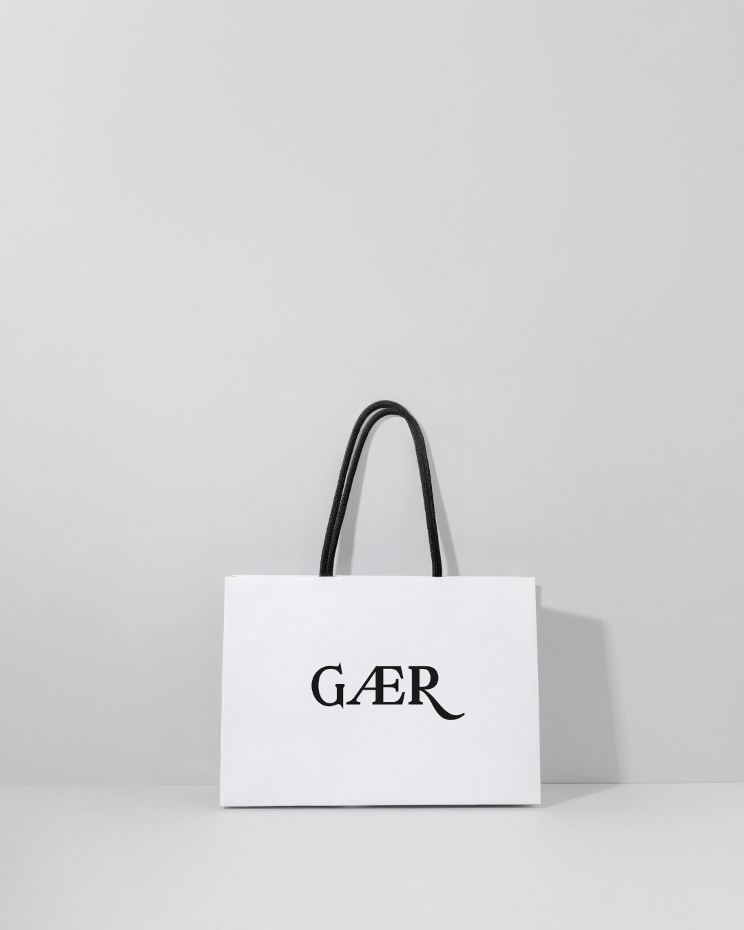 White shopping bag with 'GAER' logo on a light gray background